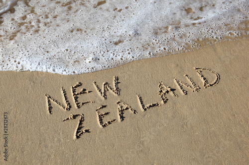 New Zealand written in the sand at the beach with wave
