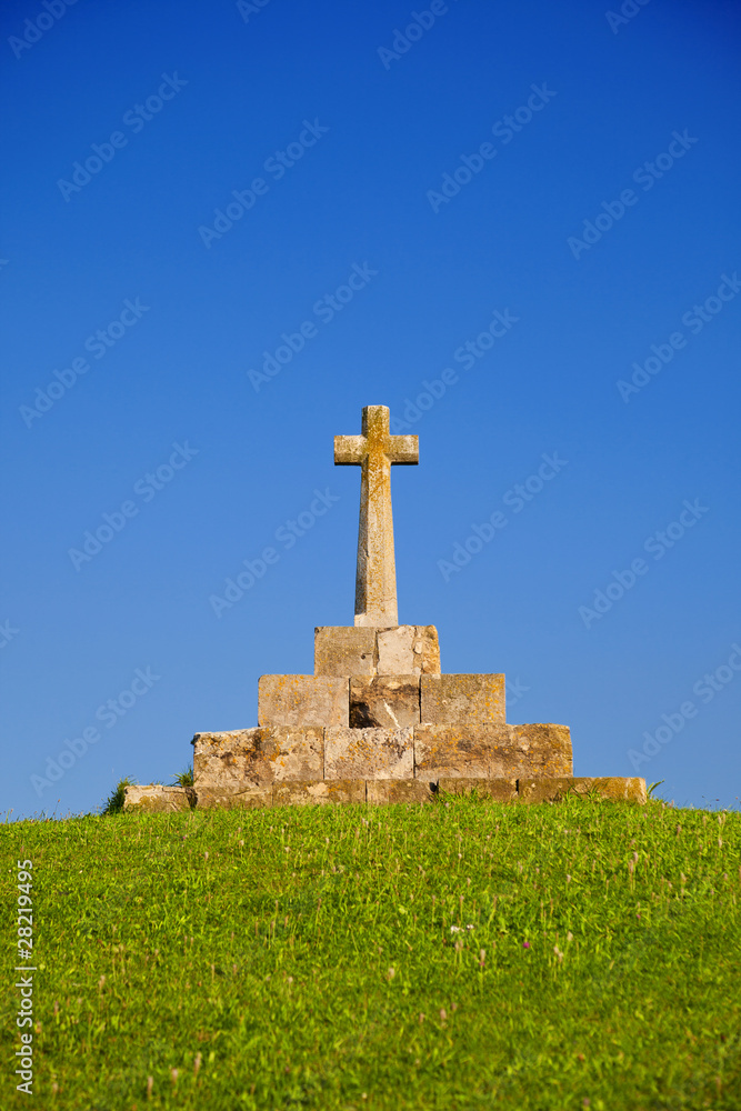 Stone cross in the top of a grassy hill Stone cross in the top of a grassy hill