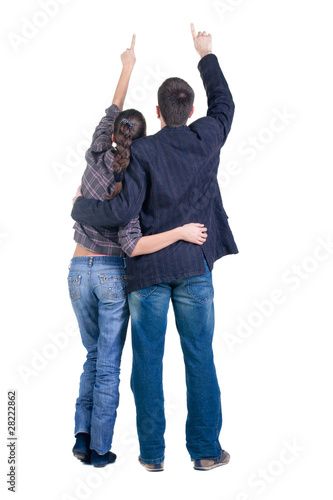 Young couple pointing at wall. Rear view