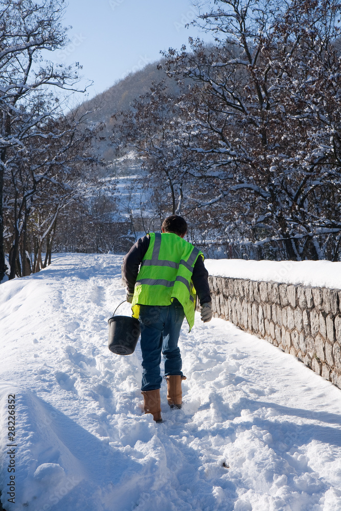 Déneigement : un employé municipal répand du sel sur un chemin couvert de neige