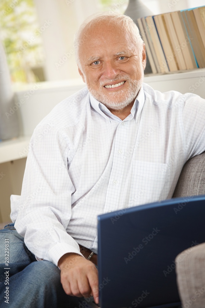 Portrait of senior man using computer on sofa Portrait of senior man using computer on sofa