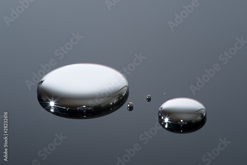 Droplets of mercury on a reflective surface.