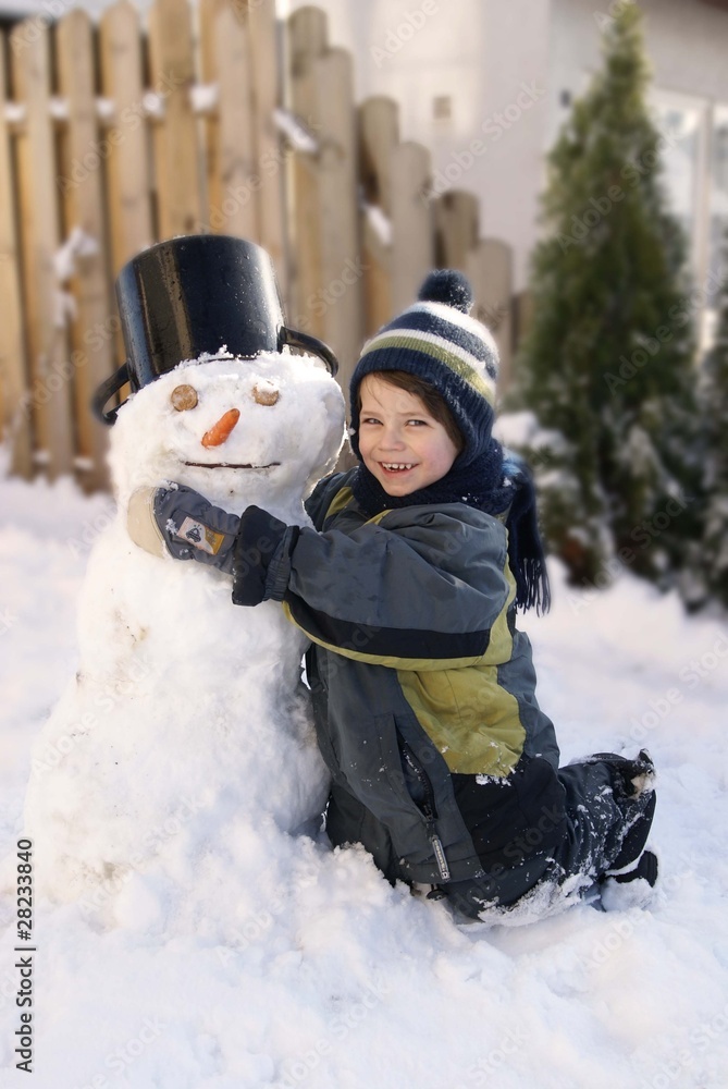 Kind umarmt lächelnd einen Schneemann Kind umarmt lächelnd einen Schneemann