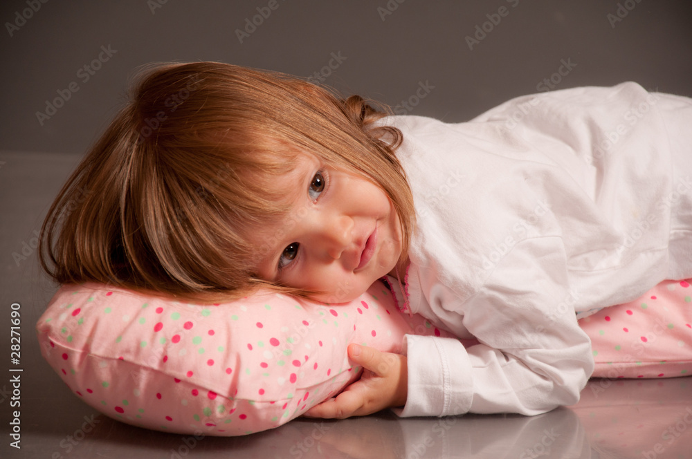 Little girl in sleeping suit lying on a pillow