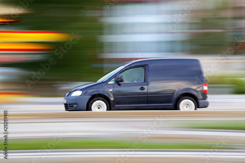Speedy dark minivan is going on road, panning and blur