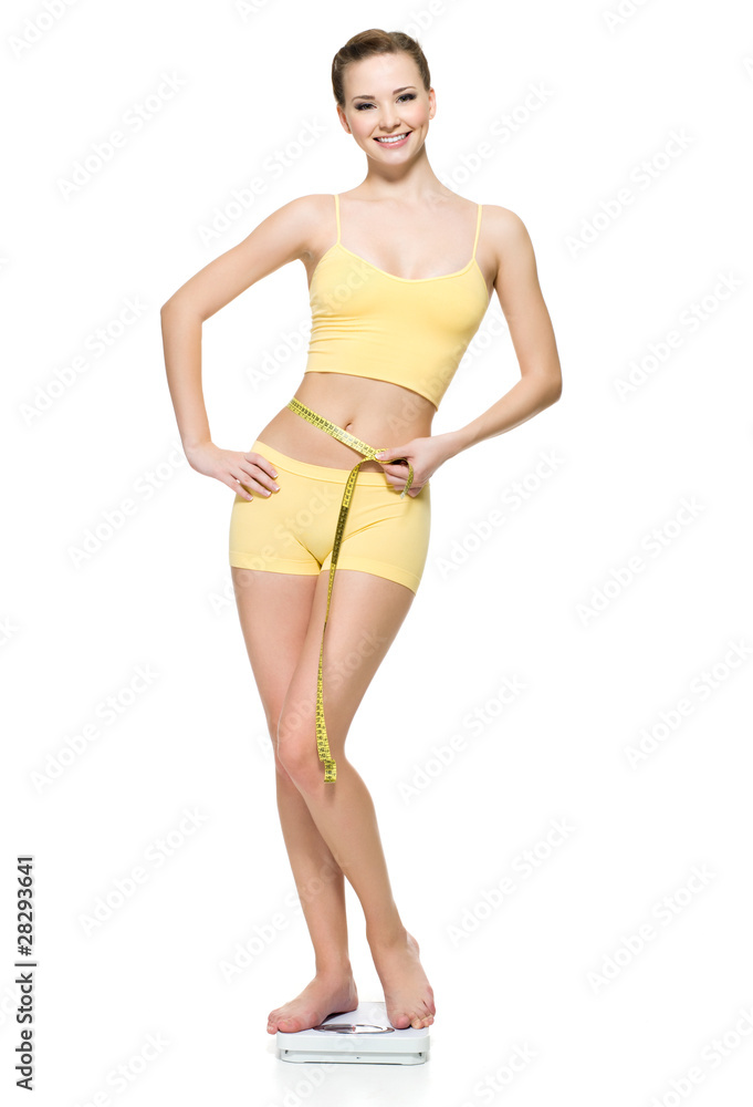 Fototapeta premium Woman standing on scales and measuring her slim waist