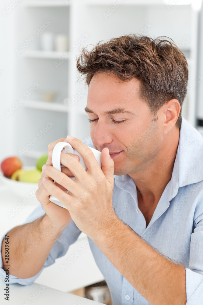 Handsome man smelling his coffee sitting in his kitchen Handsome man smelling his coffee sitting in his kitchen