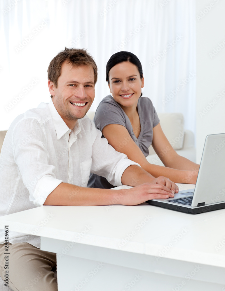 Portrait of a couple with a laptop at a table in the living room Portrait of a couple with a laptop at a table in the living room
