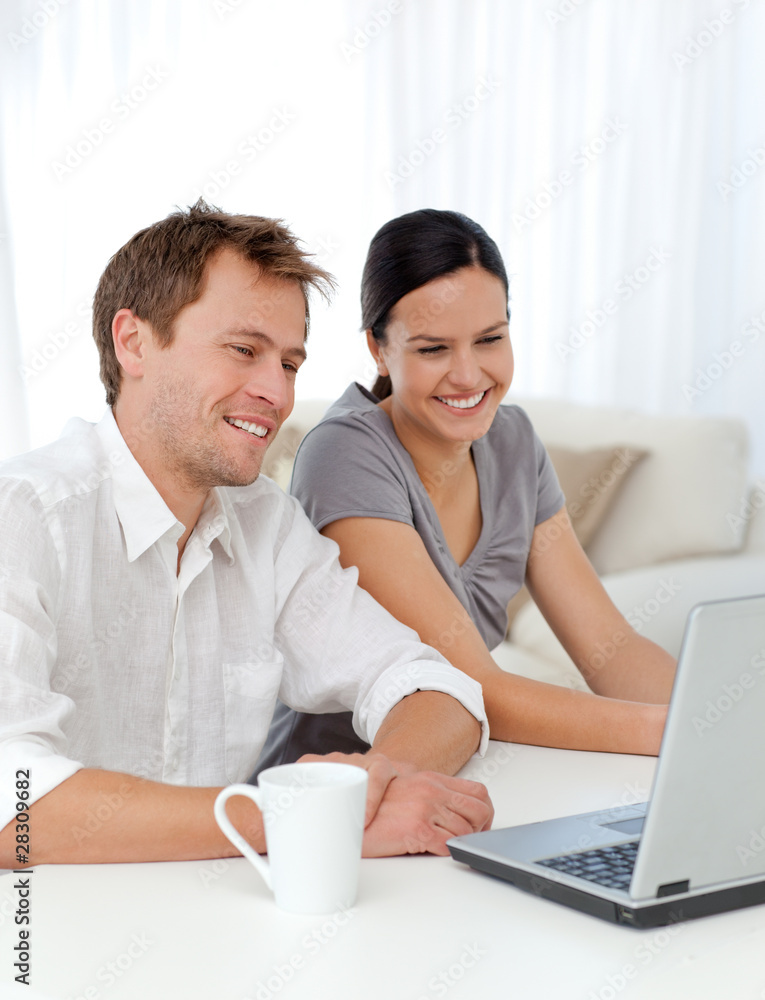 Lovely couple laughing while looking at a video on the laptop Lovely couple laughing while looking at a video on the laptop