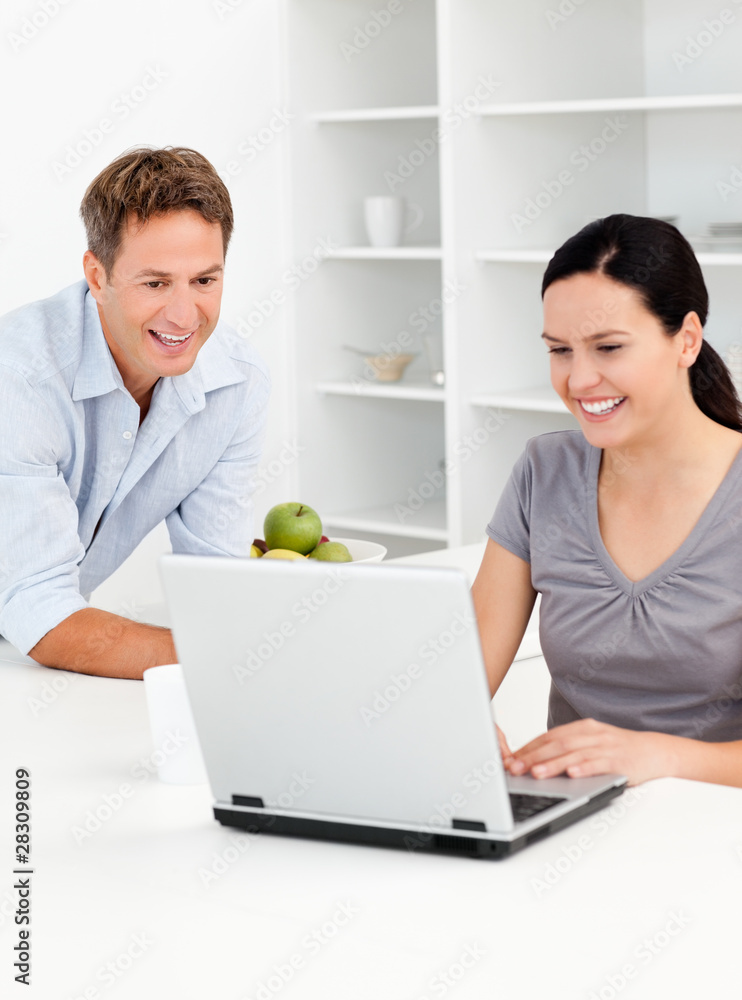 Happy couple looking at their laptop while drinking coffee Happy couple looking at their laptop while drinking coffee
