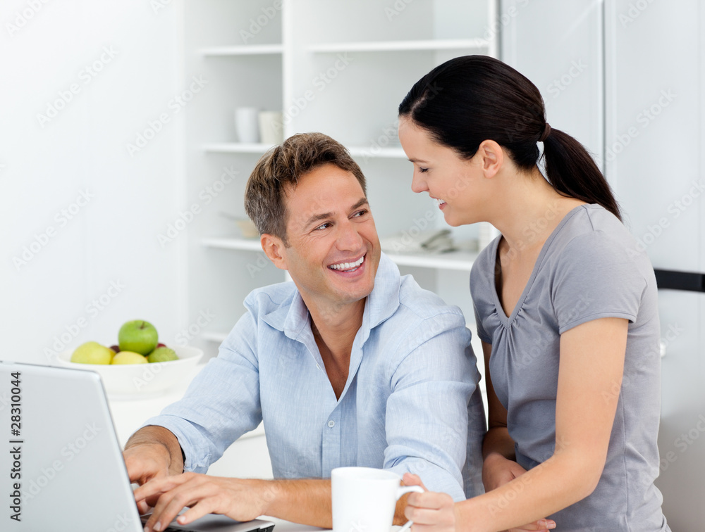 Happy couple working on their laptop in the kitchen Happy couple working on their laptop in the kitchen