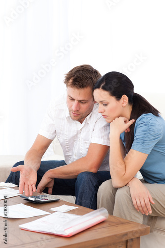 Desperate couple doing their account sitting on the sofa