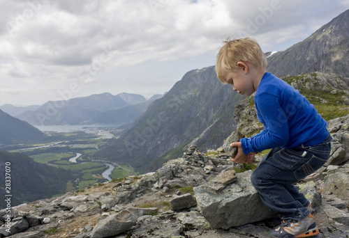 Small boy (3 years old) building a cairn