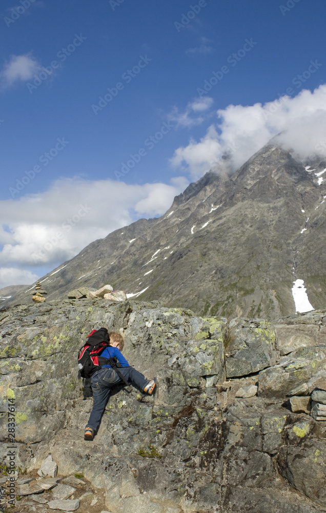 Small child climbing high mountains. Rauma, Norway