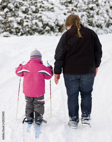 Mother teaching small child cross country skiing