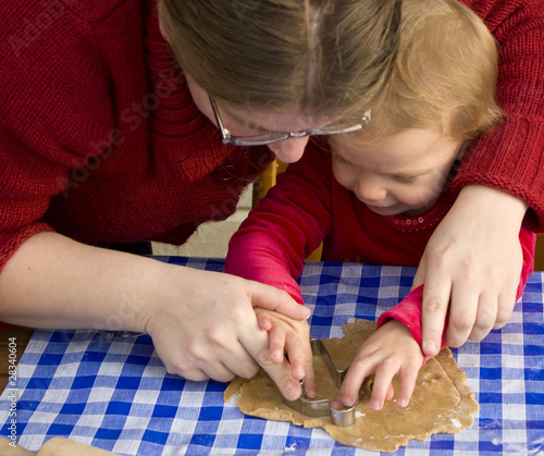 Mother helping toddler daughter ot make gingerbread cookies