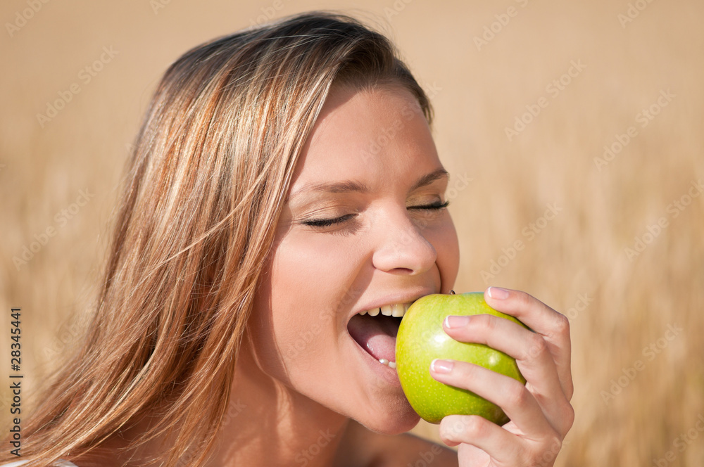 Woman in wheat field eating green apple. Summer picnic. Woman in wheat field eating green apple. Summer picnic.