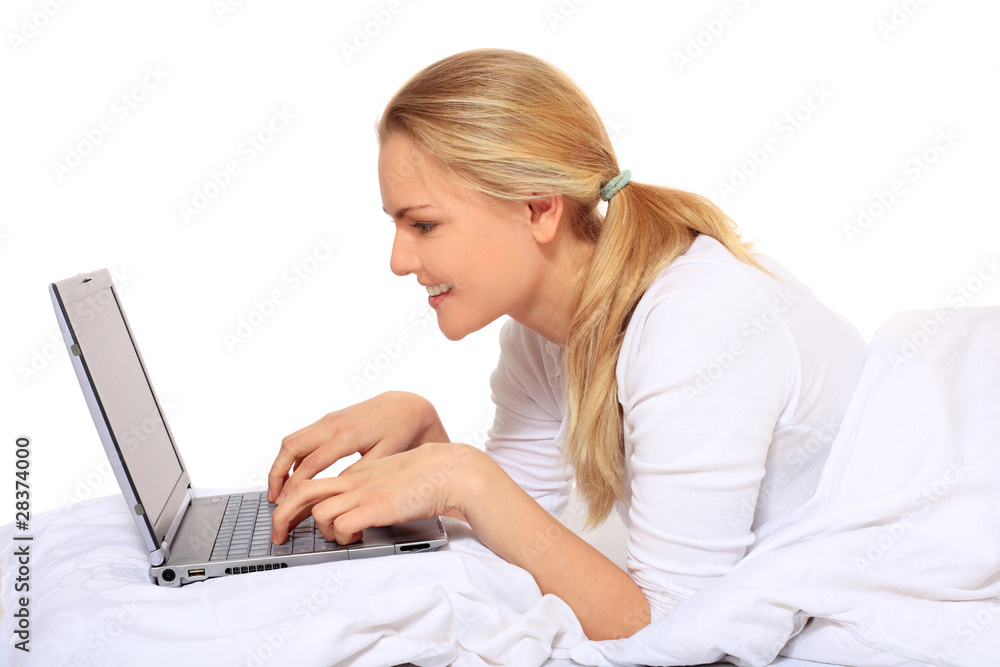 Junge Frau nutzt Notebook im Bett Junge Frau nutzt Notebook im Bett