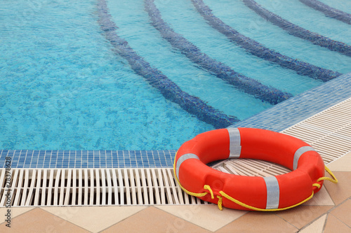 red lifebuoy with yellow ropes on tiled floor near swimming pool photo