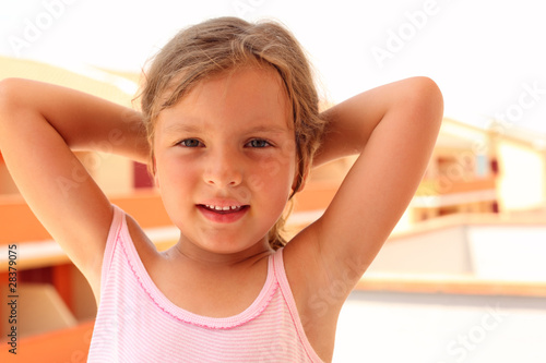 little girl in pink singlet put her hands behind head.