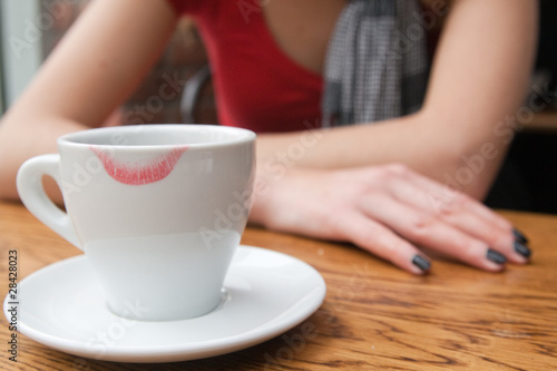 Девушка пьет кофе с белой чашки со следами губной помады