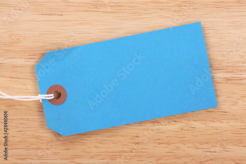 Blank blue paper luggage tag on wood background