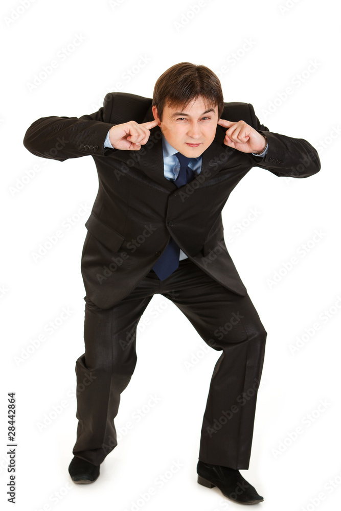 Young businessman ducking in fear and closing ears with fingers Young businessman ducking in fear and closing ears with fingers