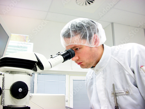 The men looks in stereomicroscope eyepieces