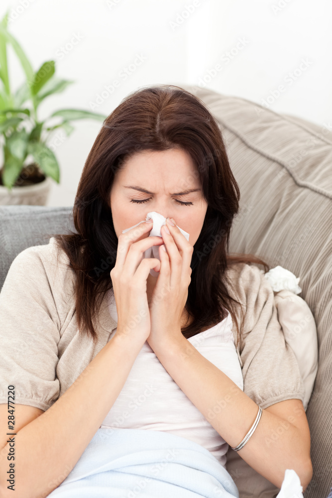 Portrait of a sick woman blowing her nose on the sofa Portrait of a sick woman blowing her nose on the sofa