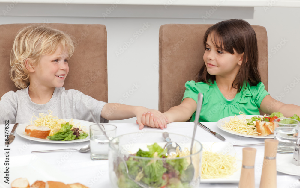 Cute brother and sister holding their hands before lunch Cute brother and sister holding their hands before lunch