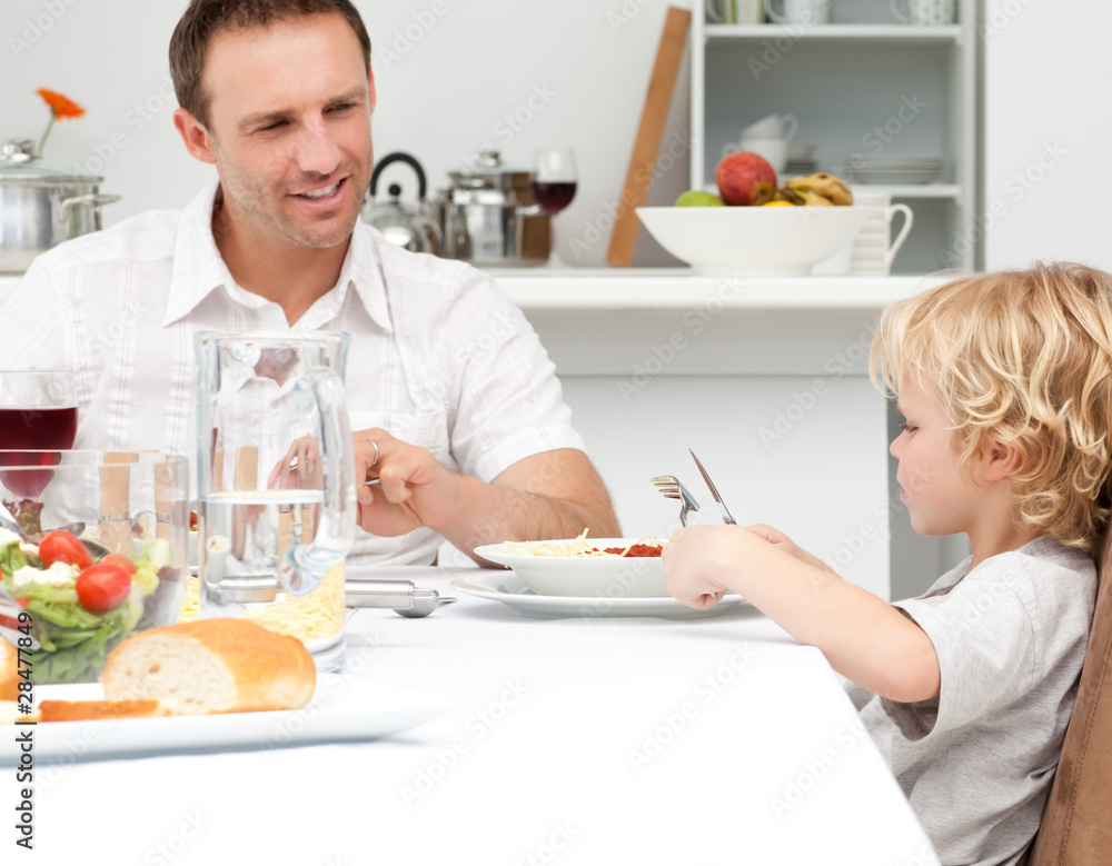 Happy dad looking at his son eating pasta Happy dad looking at his son eating pasta