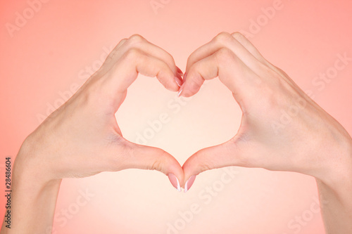 Hands making heart on red background