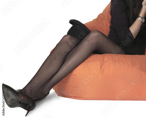 Foto Stock sexy gambe di donna seduta con collant nere velate | Adobe Stock