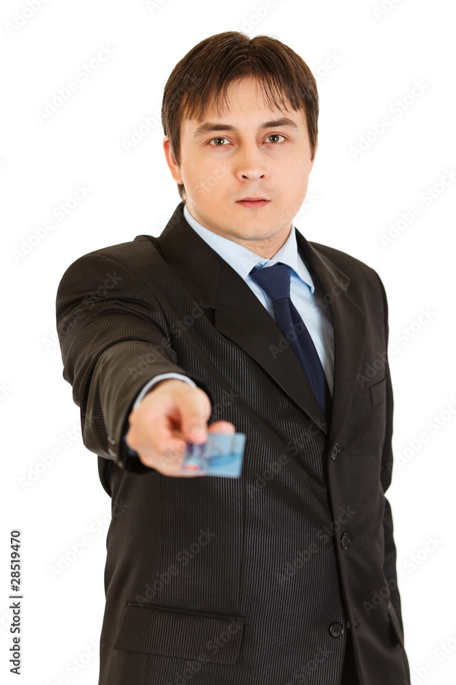 Serious young businessman giving credit card isolated on white. Serious young businessman giving credit card isolated on white.