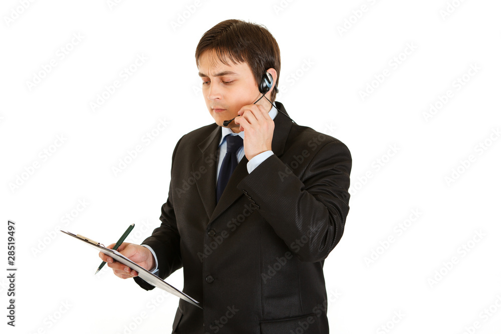 Thoughtful  young  businessman with headset  and clipboard