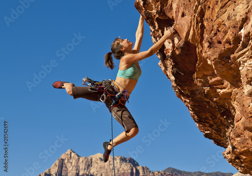 Female rock climber clinging to a cliff. Fototapet
