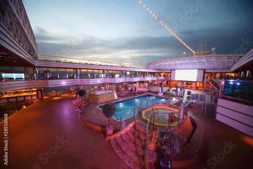 Overview of deck of  cruise ship with screen, pool and baths photo