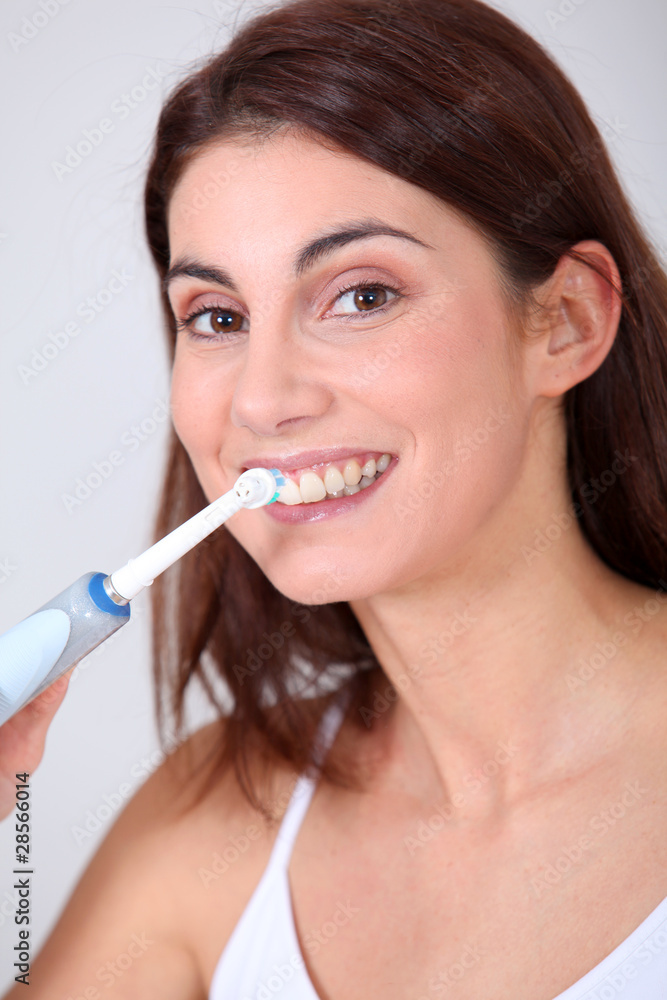 Young woman brushing her teeth with electric toothbrush Young woman brushing her teeth with electric toothbrush