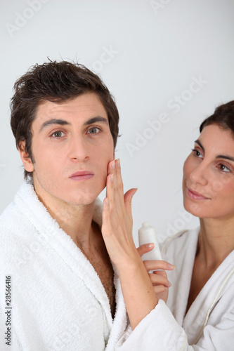 Woman applying moisturizer on boyfriend's cheek