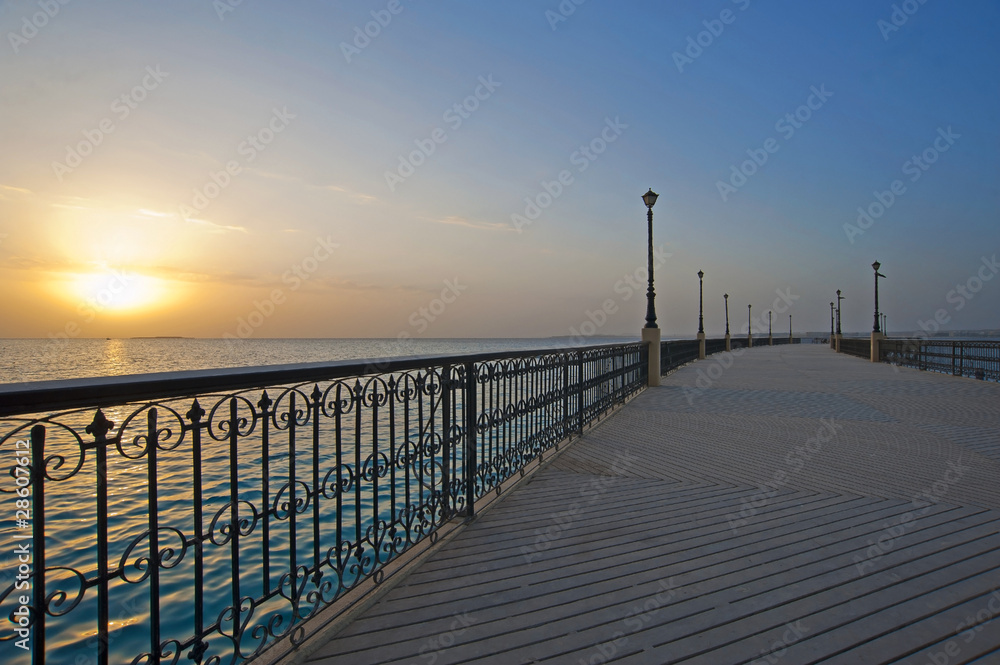 Sunrise over the ocean at a pier
