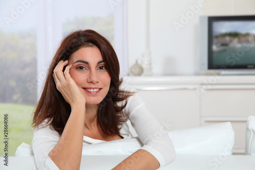 Portrait of young woman sitting in sofa watching television