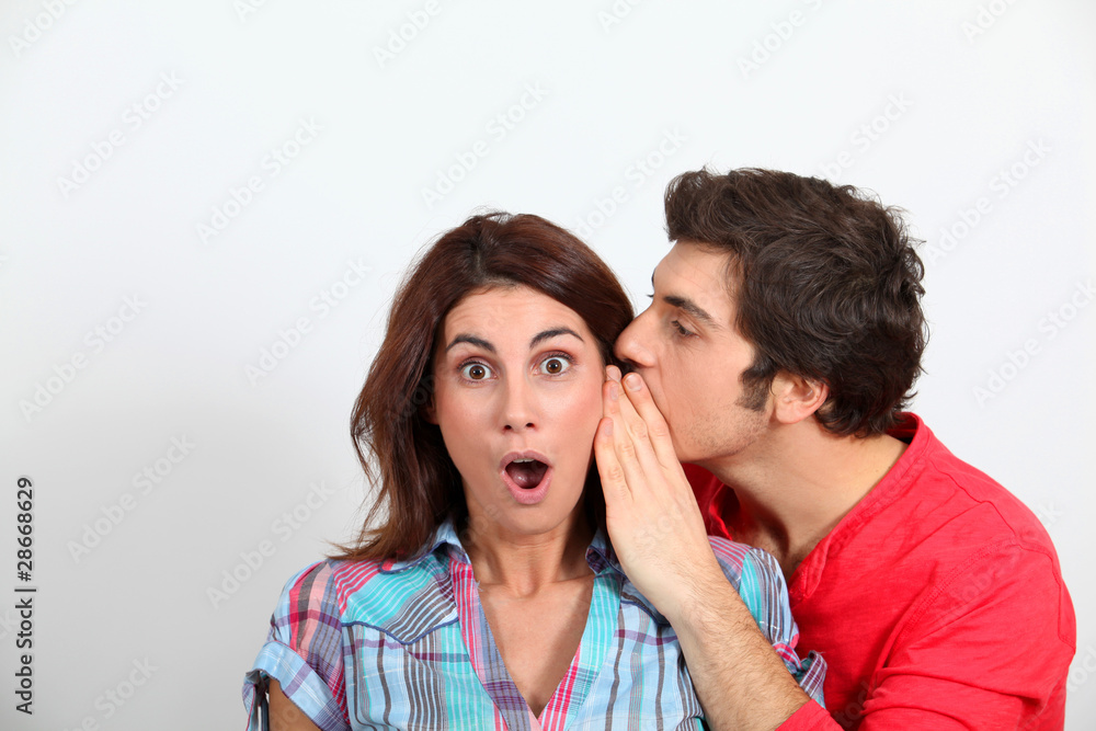 Young man whispering in his girlfriend's ear Young man whispering in his girlfriend's ear