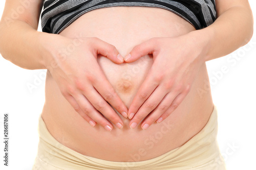 closeup of a pregnant woman showing heart with fingers © khomich