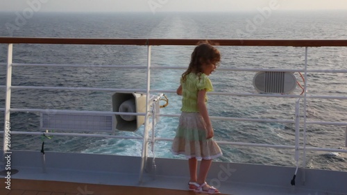 girl stands aft of cruise liner and looks at sea photo