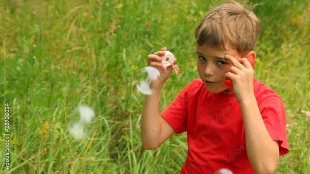 boy is enthusiastically blowing bubbles in park boy is enthusiastically blowing bubbles in park