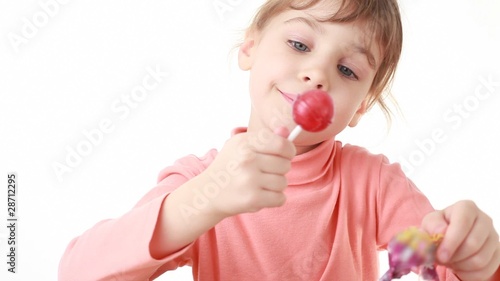 little girl removing cover and eating lollipop