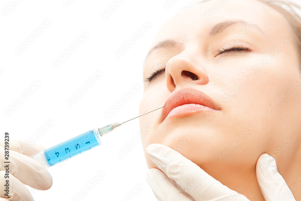 Close-up young woman receiving cosmetic injection to lips Close-up young woman receiving cosmetic injection to lips