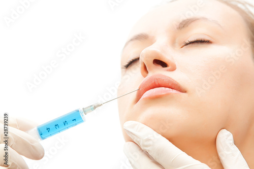 Close-up young woman receiving cosmetic injection to lips