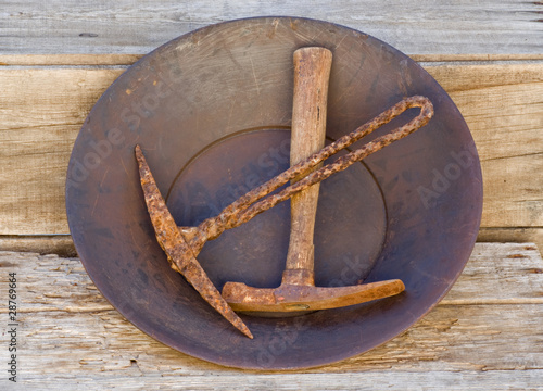 Gold Pan and old mining picks on wood shelf - top view photo