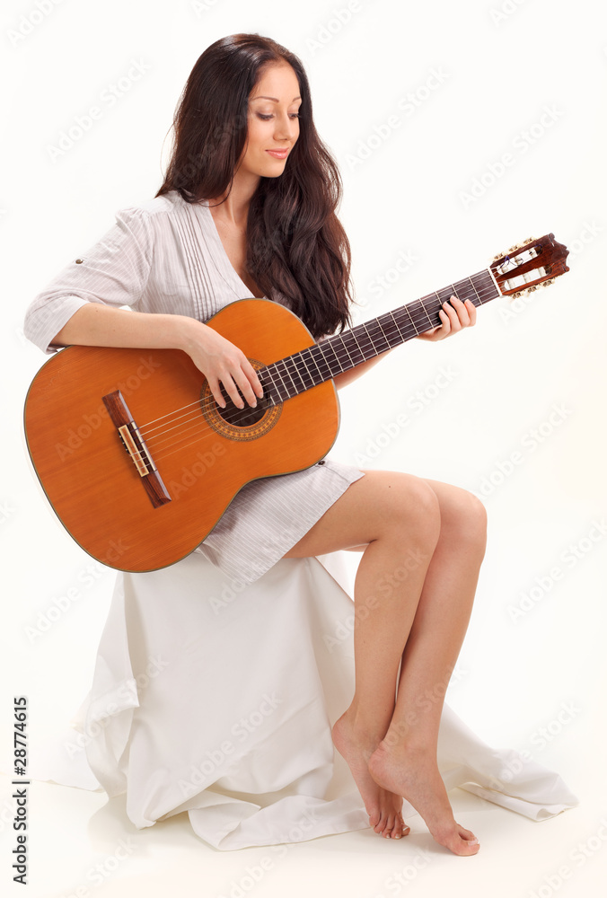 Young beautiful smiling brunette lady in white chemise playing a Young beautiful smiling brunette lady in white chemise playing a